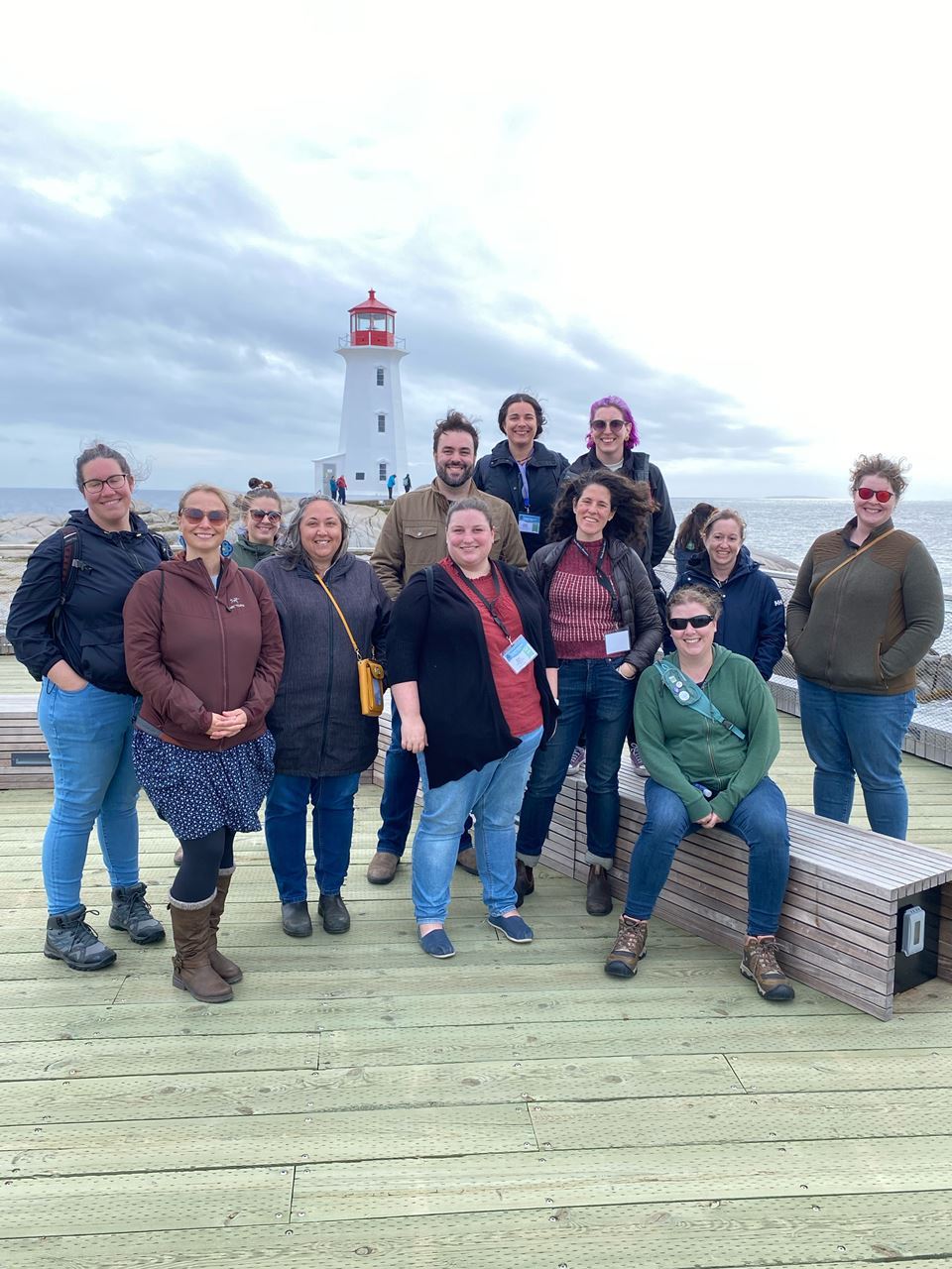 A group of interpreters stand on a wharf. Peggy’s Cove lighthouse is in the background.
